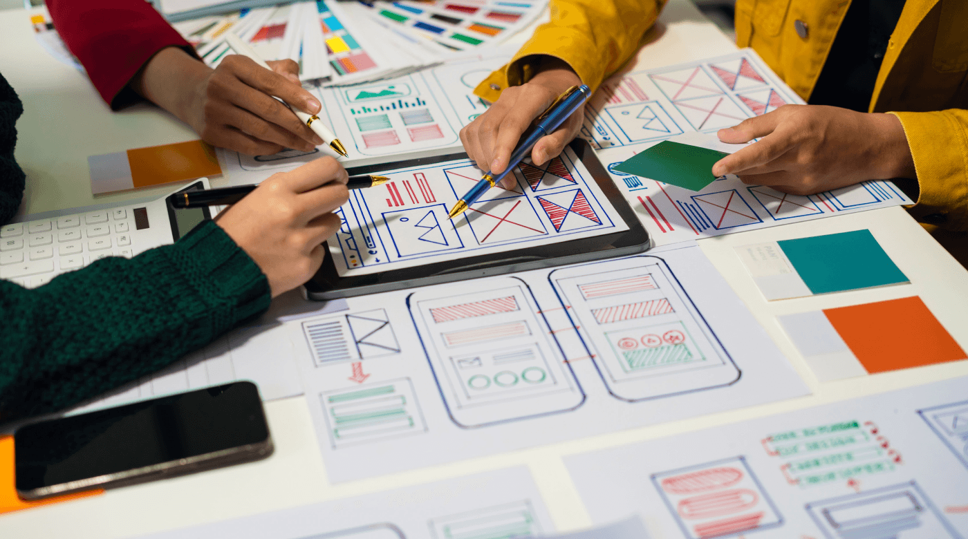 Eine Gruppe von Personen arbeitet an einem Projekt zur digitalen Produktentwicklung mit Papier und Stiften.