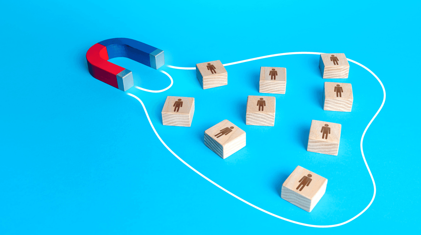 Ein Magnet mit Holzblöcken auf blauem Hintergrund, symbolisiert kreative Ansätze für effizientes Recruiting.